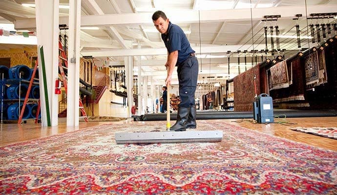 A professional rug cleaner using a squeegee to clean an area rug