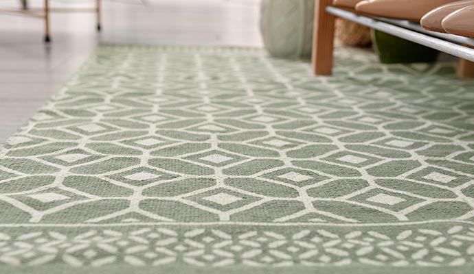 Close-up of a green viscose rug with white geometric diamond patterns