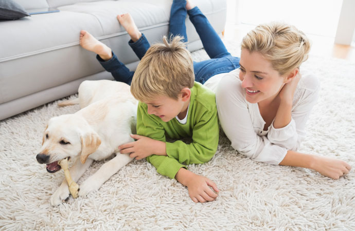 Happy mother and son with puppy on a freshly cleaned silk rug.