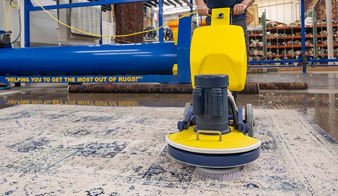 person cleaning a colorful rug professionally.