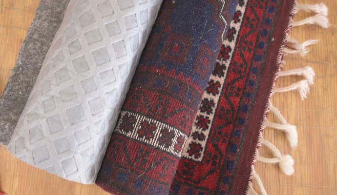 Rolled patterned area rug showing an absorbent pad backing