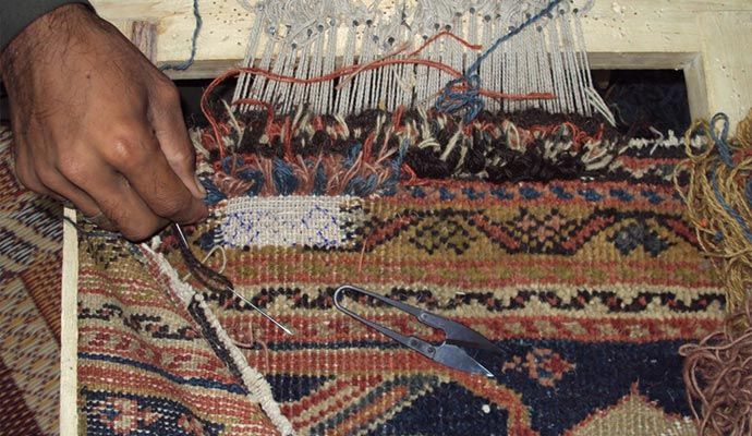 Person repairing rug with equipment